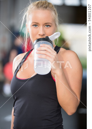 Blonde girl drinks water at fitness gym center Blonde girl drinks water at fitness gym center 54801107
