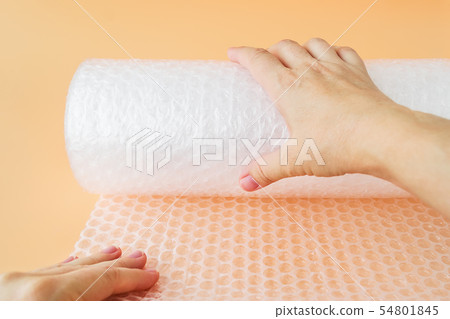Woman hands unwind a roll of bubble wrap 54801845