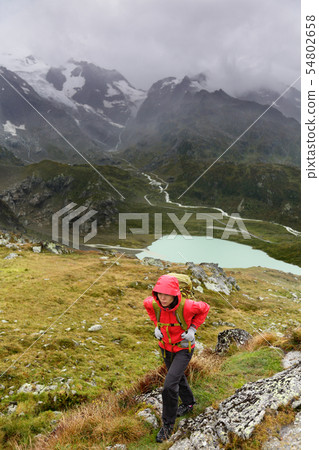 Hiker hiking on trek with backpack in rain 54802658