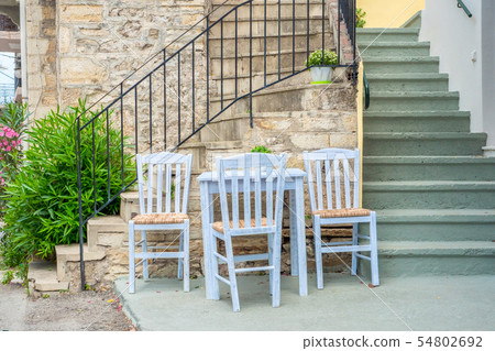 Table with chairs near the stairs leading up to 54802692