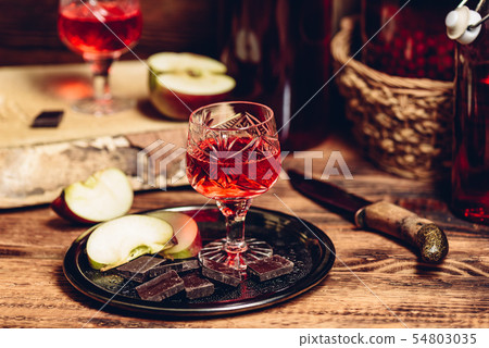 Glass of homemade currant nalivka and chocolate with apple 54803035