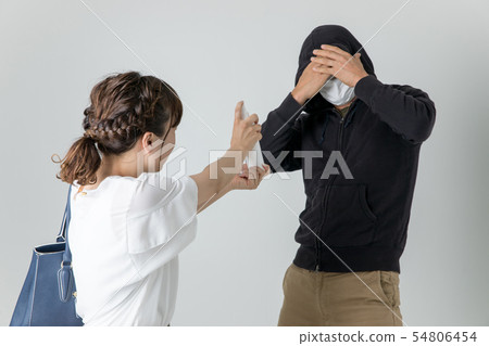 Woman applying crime spray to criminal 54806454