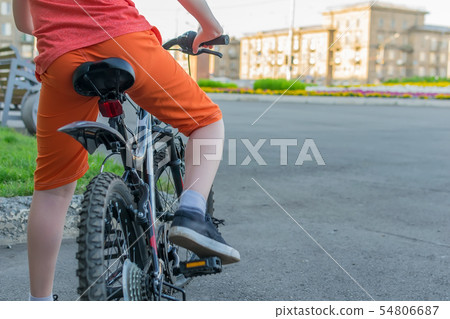 view of a teenager who sits on a bike view of a teenager who sits on a bike 54806687