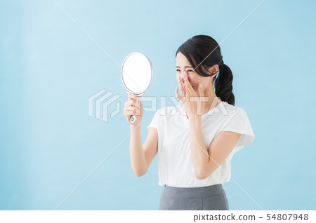 Woman looking at a mirror (blue background) Woman looking at a mirror (blue background) 54807948