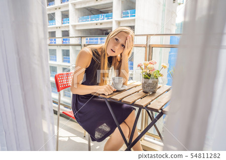 Young woman on the balcony annoyed by the building works outside. Noise concept. Air pollution from 54811282