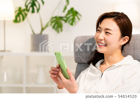 看智能手機的婦女在屋子裡 看智能手機的婦女在屋子裡 54814520
