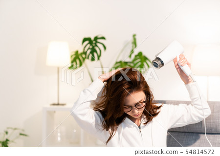 A woman drying her hair with a dryer. A woman drying her hair with a dryer. 54814572