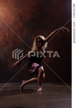 Photo of young dancing blonde woman in black dress on brown background Photo of young dancing blonde woman in black dress on brown background 54816190