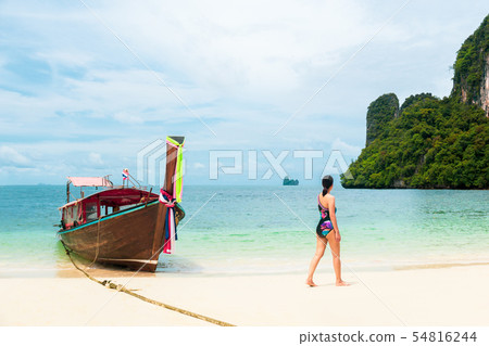 Woman in bikini walking on the beach with long tail boat in tropical island. 54816244