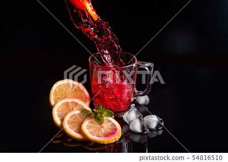 Hibiscus cold tea pouring into glass with ice, 54816510