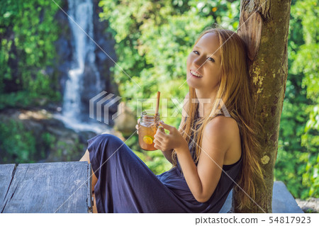 Closeup portrait image of a beautiful woman drinking ice tea with feeling happy in green nature and 54817923