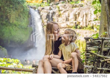 Mom and son tourists on the background of a waterfall. Traveling with kids concept. What to do with Mom and son tourists on the background of a waterfall. Traveling with kids concept. What to do with 54817982