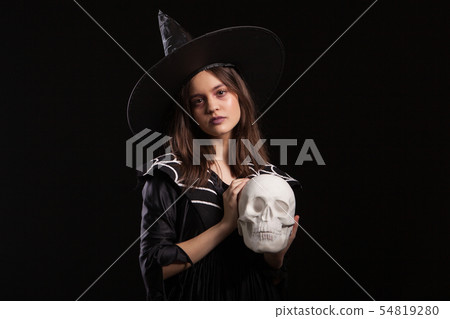 Beautiful child dressedup in a black dress for halloween carnival with a human skull in hands Beautiful child dressedup in a black dress for halloween carnival with a human skull in hands 54819280