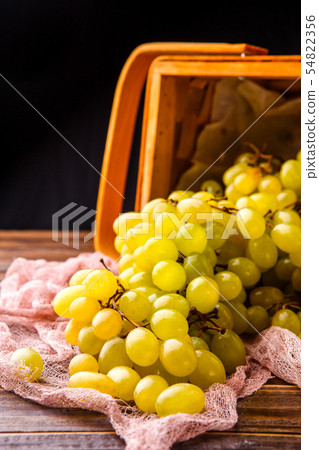 Picture of wooden basket with green grapes on table 54822356