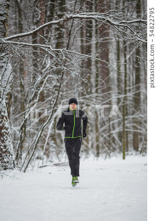 Picture of man in sportswear, black hat jogging in winter 54822795