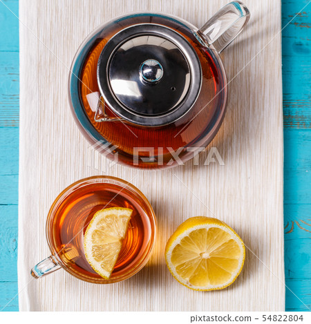 Glass cup of tea with lemon and glass teapot. 54822804