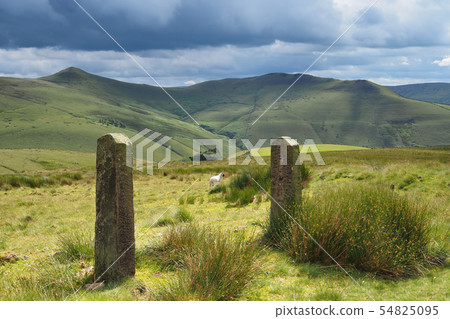 View over sunlit mountains and rock gate posts with dark clouds overhead, Peak District, UK View over sunlit mountains and rock gate posts with dark clouds overhead, Peak District, UK 54825095