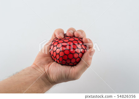 Male hand squeezing stress ball 54826356