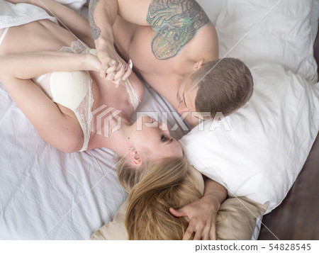 Young couple lying in bed and looking at each other lovingly and hold hands. Love and relationships 54828545