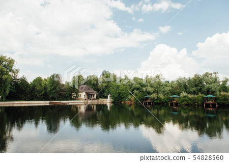 beautiful country house near the lake on a sunny day with clouds beautiful country house near the lake on a sunny day with clouds 54828560