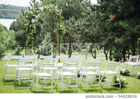 Outgoing wedding ceremony. Decor Studio. white wooden chairs on a green lawn. 54828659