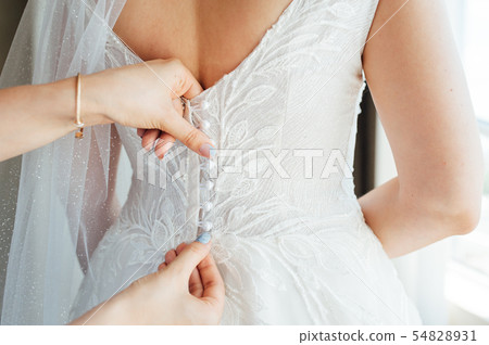 Bridesmaid preparing bride for the wedding day. Wedding concept 54828931