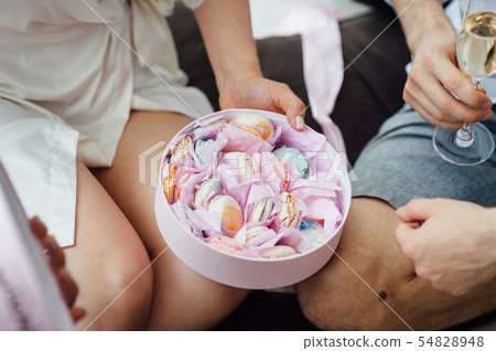 Portrait of beautiful happy couple man and woman are eating macaron biscuits Portrait of beautiful happy couple man and woman are eating macaron biscuits 54828948