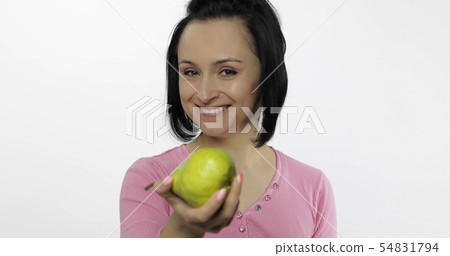 Young beautiful woman with big, fresh, juicy, green pear. Offer bite to viewer 54831794