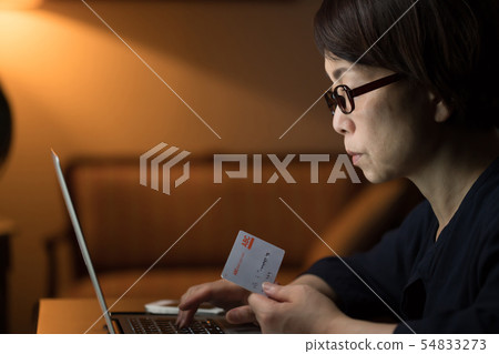 Woman using a computer at night Woman using a computer at night 54833273