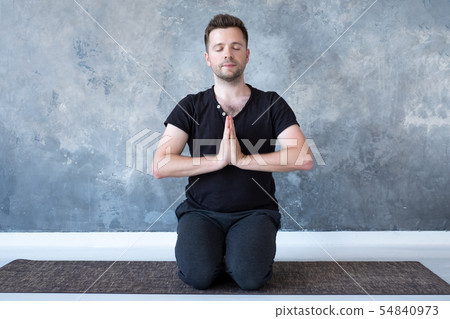Young sporty man practicing yoga lesson sitting in vajrasana pose Young sporty man practicing yoga lesson sitting in vajrasana pose 54840973