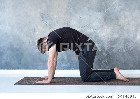 Young yogi men practices yoga asana bitilasana or cat cow pose Young yogi men practices yoga asana bitilasana or cat cow pose 54840983
