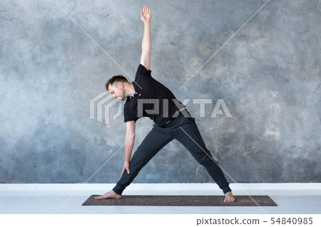 Man beginner practicing yoga doing trikonasana pose. Man beginner practicing yoga doing trikonasana pose. 54840985