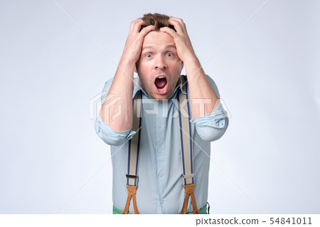 Shocked face of young european man in blue shirt and suspenders 54841011