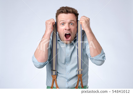 Shocked face of young european man in blue shirt and suspenders Shocked face of young european man in blue shirt and suspenders 54841012