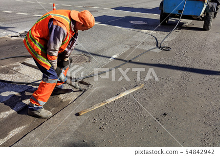 A worker clears a portion of asphalt A worker clears a portion of asphalt 54842942