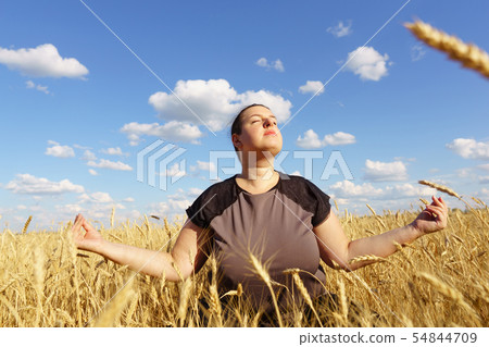 Overweight woman meditating sitting in the field Overweight woman meditating sitting in the field 54844709