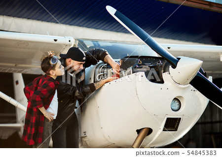 teenager boy watching his dad making repair works of small airplane 54845383