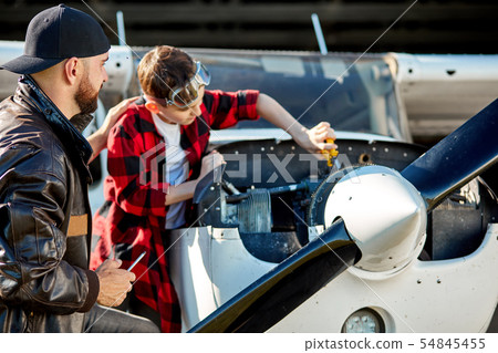 father pats his kid on the back for his progress in fixing works for airplane father pats his kid on the back for his progress in fixing works for airplane 54845455