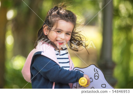 Cute girl enjoying on playground in the park in summertime. Cute girl enjoying on playground in the park in summertime. 54846953