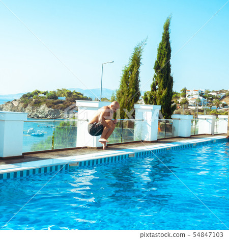 man jumps in swimpool man jumps in swimpool 54847103