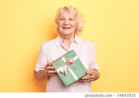 beautiful old lady holding a gift box and smiling beautiful old lady holding a gift box and smiling 54847835