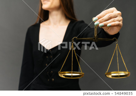 Serious woman holding the justice scale on dark Serious woman holding the justice scale on dark 54849035