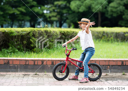 A girl playing with a bicycle 54849234