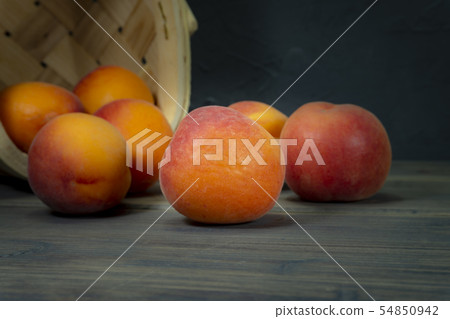 Fresh peaches spilling out of tipped wicker basket 54850942