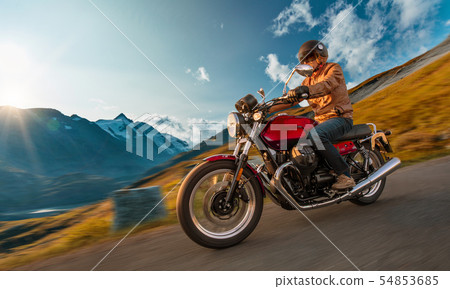 Motorcycle driver riding in Alpine highway, Nockalmstrasse, Austria, Europe. Motorcycle driver riding in Alpine highway, Nockalmstrasse, Austria, Europe. 54853685