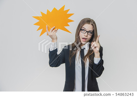 Young woman is holding a orange speech bubble, which is star-shaped, isolated, on the white Young woman is holding a orange speech bubble, which is star-shaped, isolated, on the white 54863243