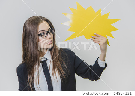 Young woman is holding a yellow speech bubble, which is star-shaped, isolated, on the white Young woman is holding a yellow speech bubble, which is star-shaped, isolated, on the white 54864131