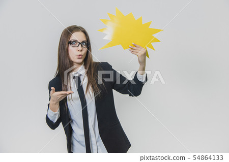 Young woman is holding a yellow speech bubble, which is star-shaped, isolated, on the white Young woman is holding a yellow speech bubble, which is star-shaped, isolated, on the white 54864133
