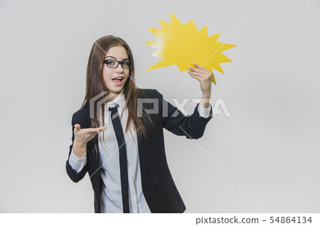 Young woman is holding a yellow speech bubble, which is star-shaped, isolated, on the white Young woman is holding a yellow speech bubble, which is star-shaped, isolated, on the white 54864134