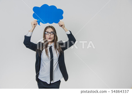 Young woman is holding a blue speech bubble over herself, which is cloud-shaped, isolated, on the Young woman is holding a blue speech bubble over herself, which is cloud-shaped, isolated, on the 54864337